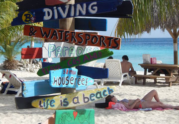 Ein Wegweiser mit Schildern an einem Strand in Curacao