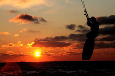 Ein Kitesurfer in der Abenddämmerung bei einem Sprung