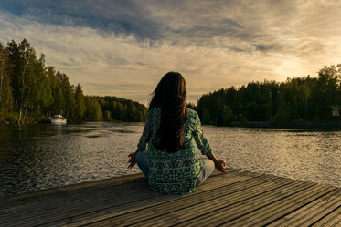 Frau am See sitzend und meditierend